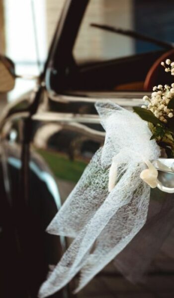 Fresh beautiful rose hanging on handle of vintage cabriolet on street
